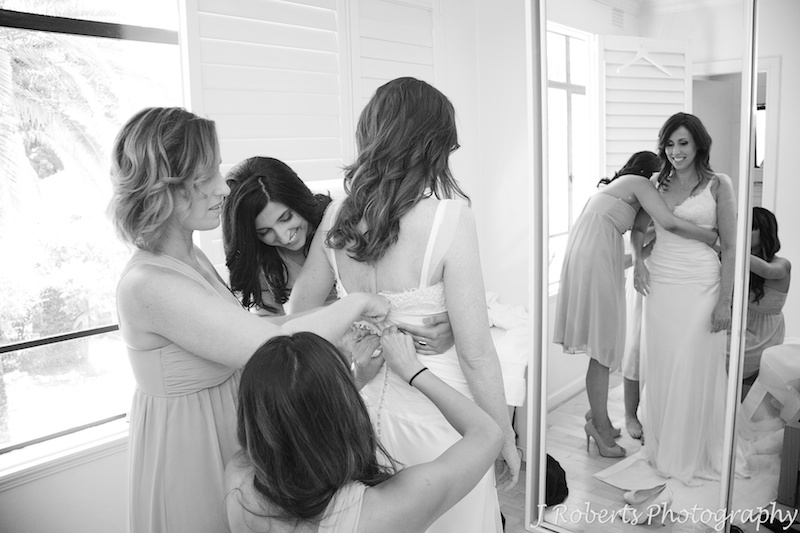 Bridesmaids helping the bride into her dress - wedding photography sydney